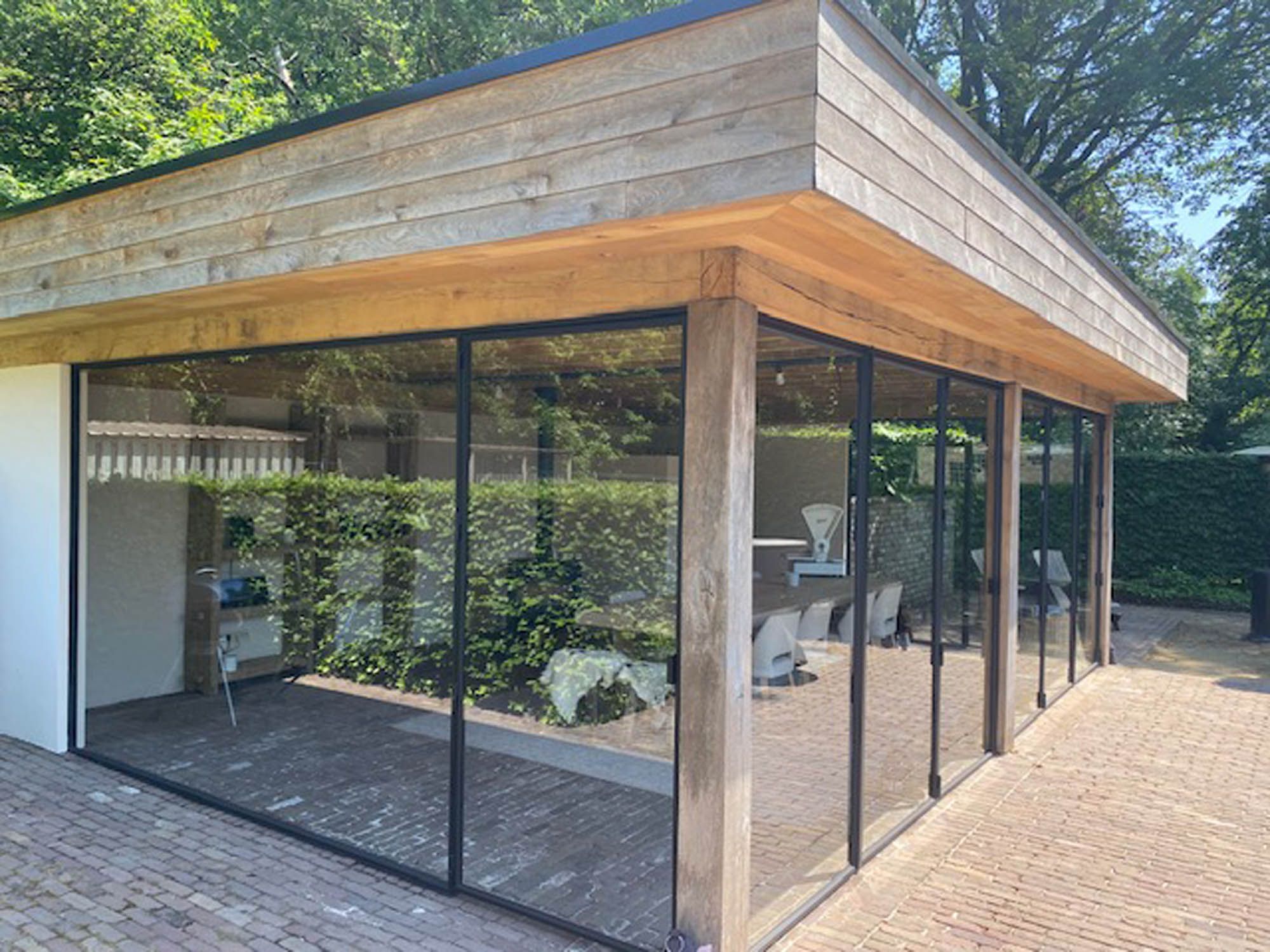 Tuinkamer met houten dakrand en volledig gereinigde glaswanden