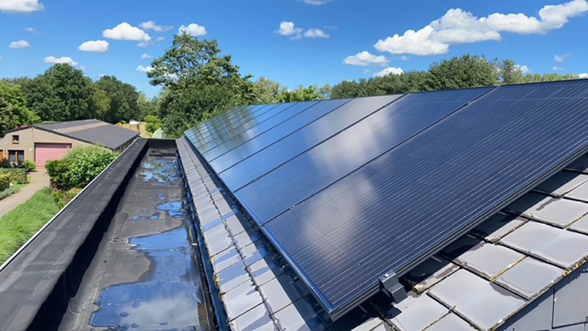 Zonnepanelen op een hellend dak na reiniging, met gereinigde dakgoot