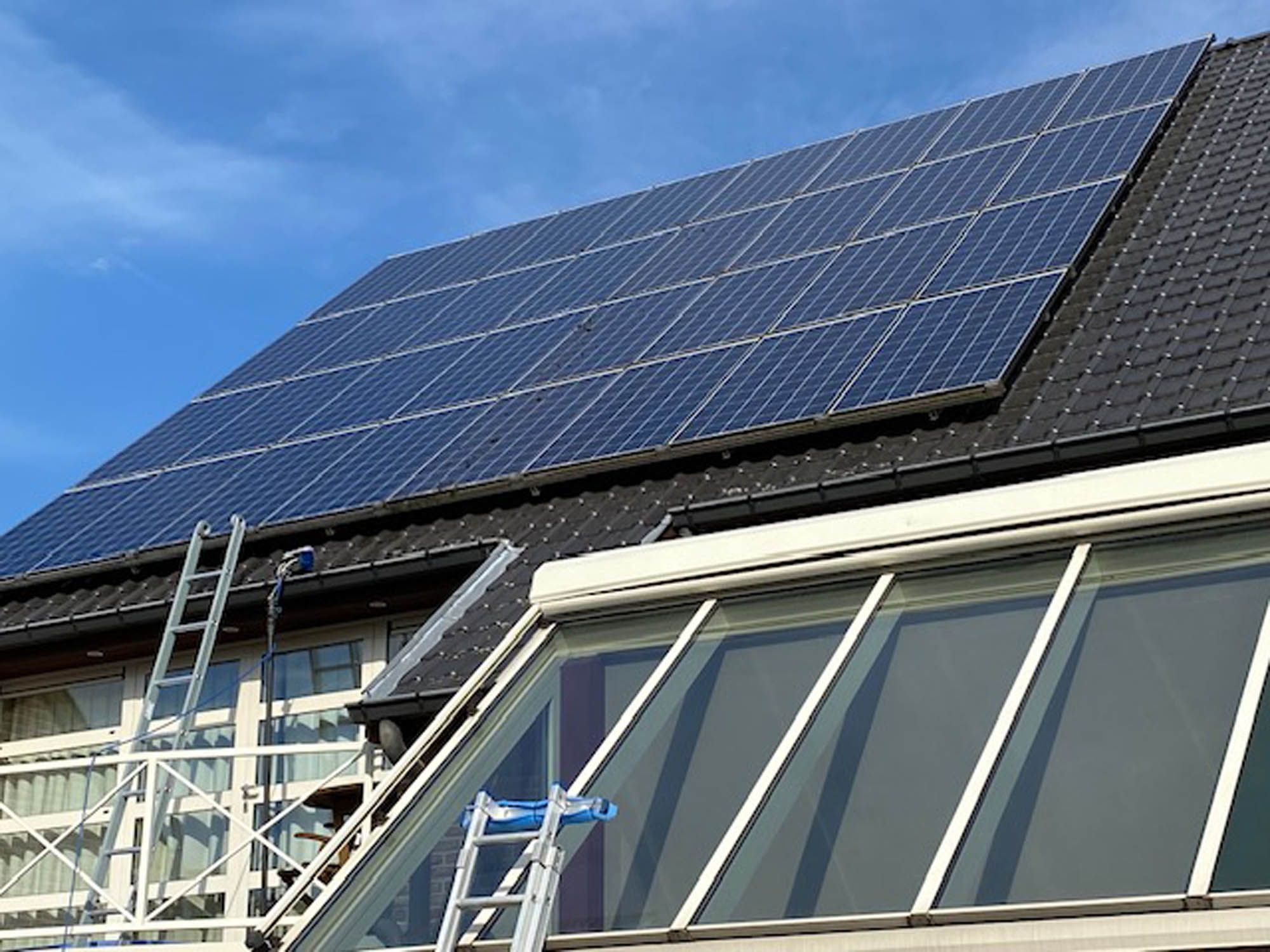 Zonnepanelen en glazen verandadak gereinigd met ladder en rolsteiger