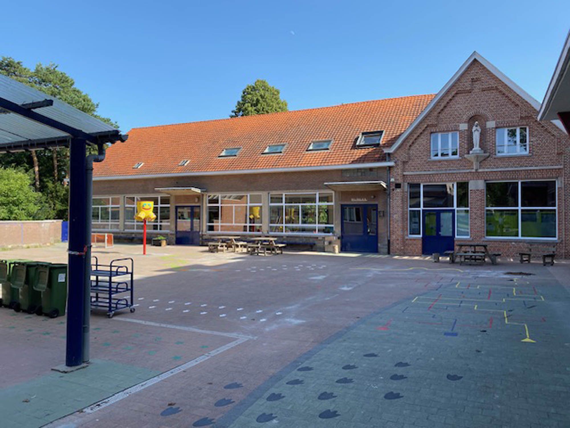 Schoolgebouw met rode dakpannen en gereinigde ramen aan de speelplaats