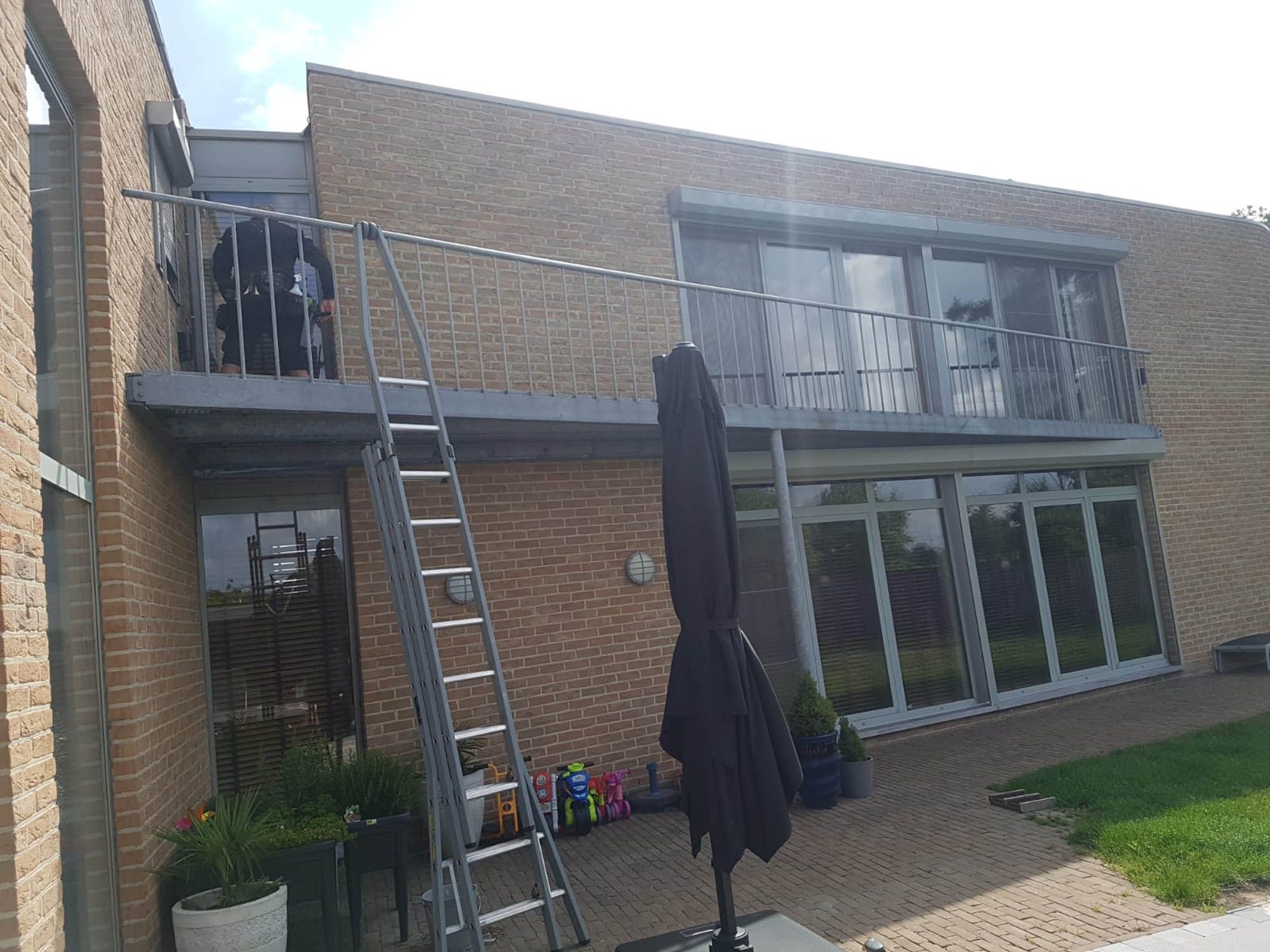 Woning met terras en balkon, ladder opgesteld voor het reinigen van de ramen