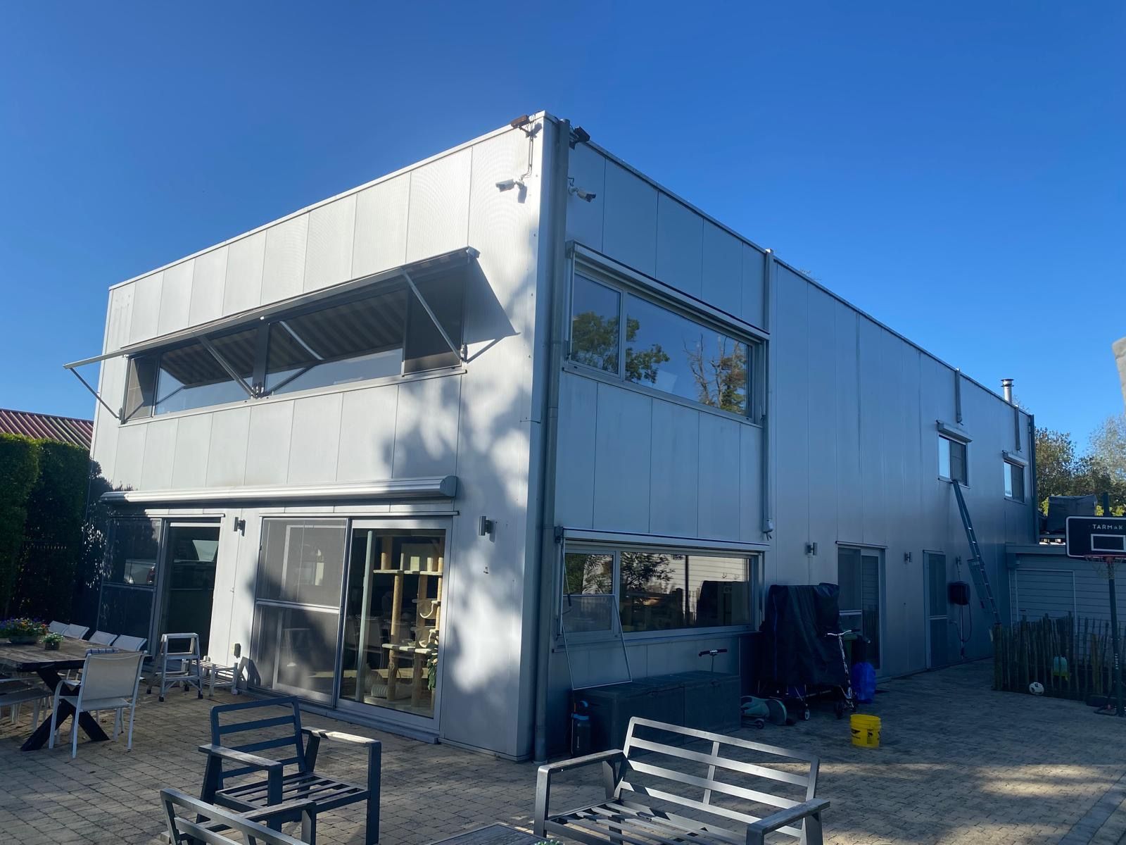 Aluminium gevel van het Altimo-gebouw met grote raampartijen en schuiframen, ladder opgesteld voor het reinigen van de bovenramen
